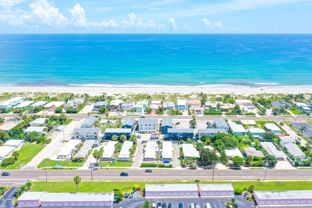 A beachfront view of a small town with buildings and a parking lot.