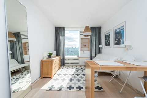 A well-lit, modern bedroom with a large window and a view of the city.