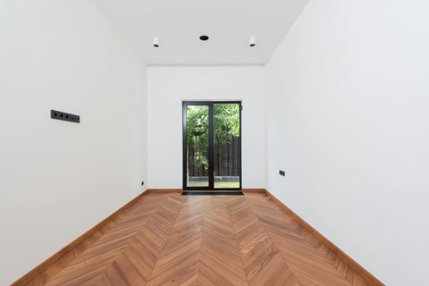 A room with a wooden floor and a glass door leading outside.