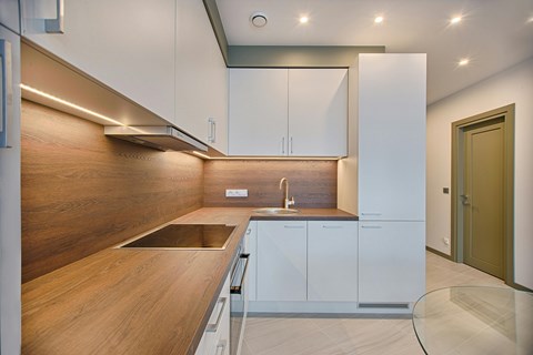 A modern kitchen with white cabinets and a wooden countertop.