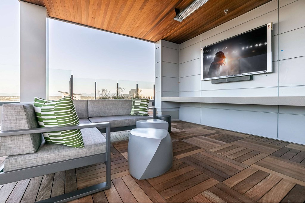 A modern living room with a grey sofa and a television on the wall.