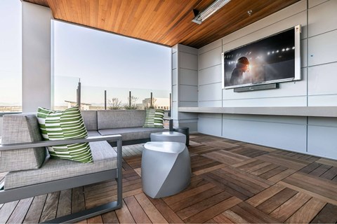 A modern living room with a grey sofa and a television on the wall.