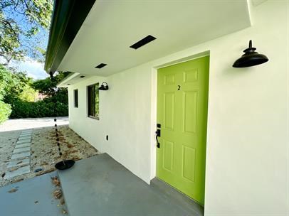 A green door is on the side of a white building.