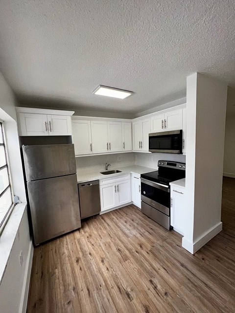 A kitchen with white cabinets and a wooden floor.