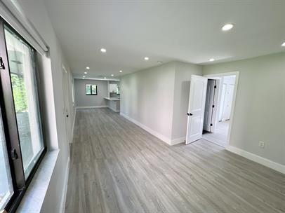 A long, empty room with wood flooring and white walls.