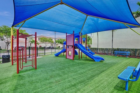 Gate enclosed, covered playground with a blue slide and a green canopy.