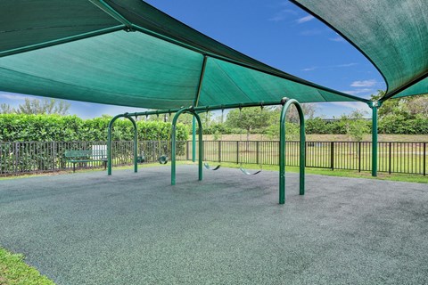Gate enclosed, covered playground with swings.