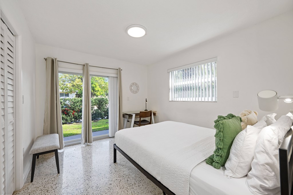 A bedroom with a bed, nightstand, and chair.