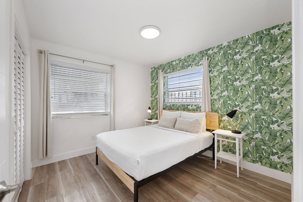 A bedroom with a bed, nightstand, and a wallpapered wall.