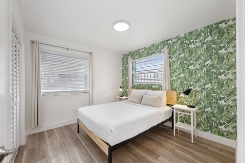 A bedroom with a bed, nightstand, and a wallpapered wall.