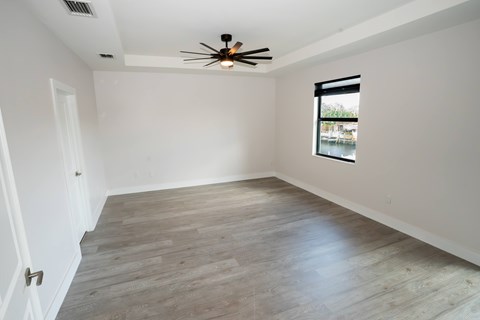 A room with a ceiling fan and a window overlooking a pool.