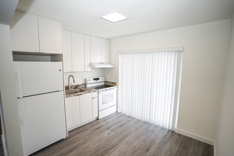 A kitchen with white cabinets and a refrigerator.