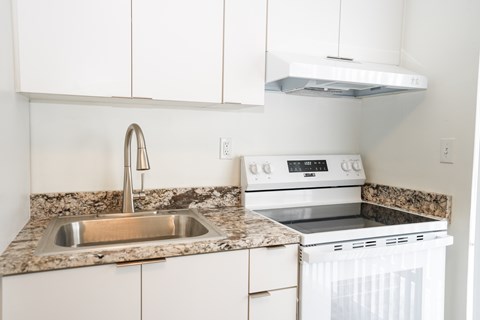 A kitchen with a white oven and sink.