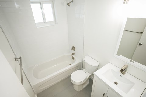 A white bathroom with a toilet, sink, and bathtub.