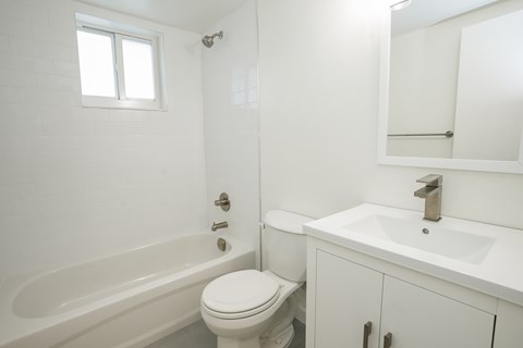 A white bathroom with a toilet, sink, and bathtub.