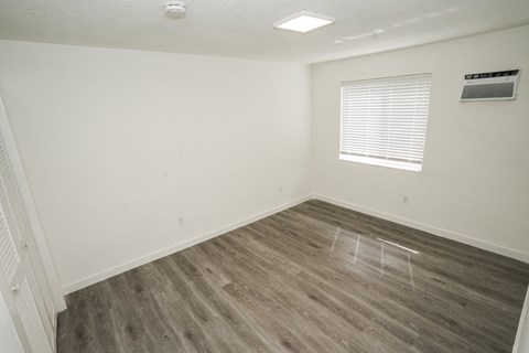 A room with a window and wooden flooring.