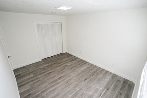 A room with a white door and wooden flooring.