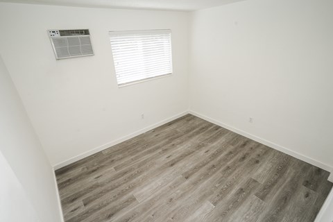 A room with a window and wooden flooring.