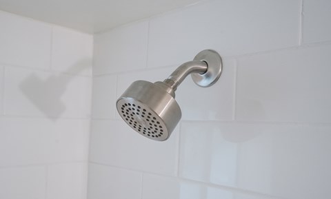 A shower head mounted on a white tiled wall.