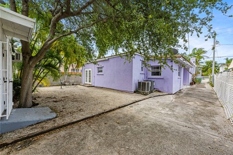 A purple house with a white fence and a tree in front.