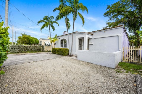 A white house with a gravel driveway and a gate.