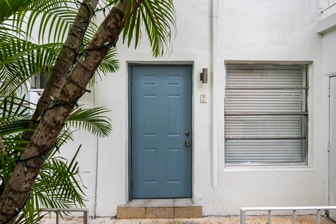 A blue door is on the left side of a white building.
