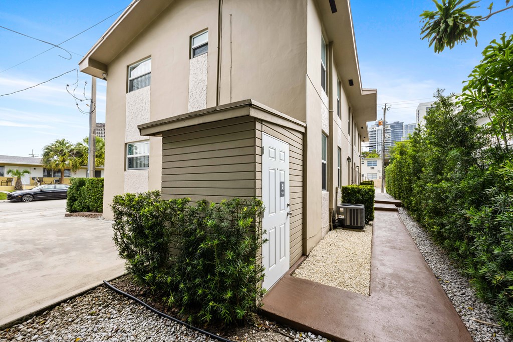 A modern house with a white door and a gravel pathway leading to it.