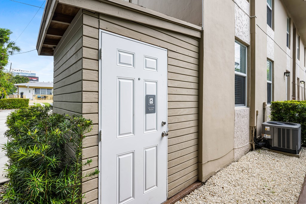 A white door with a black handle is on a beige house.