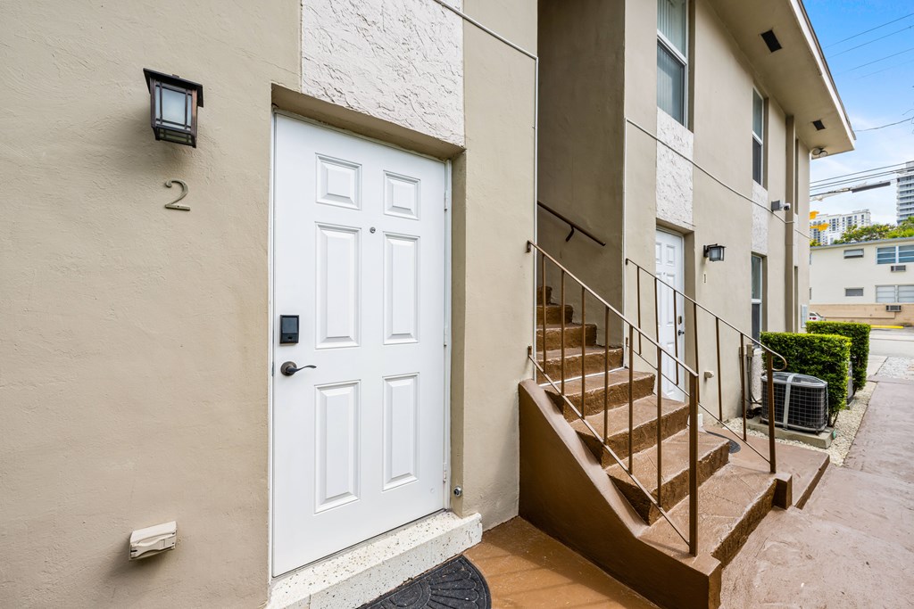 A white door with a black handle is on the left side of a staircase.