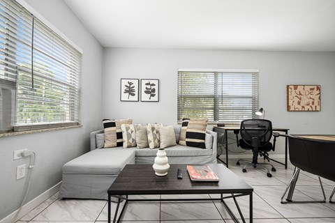 A modern living room with a grey couch, a black coffee table, and a black chair.