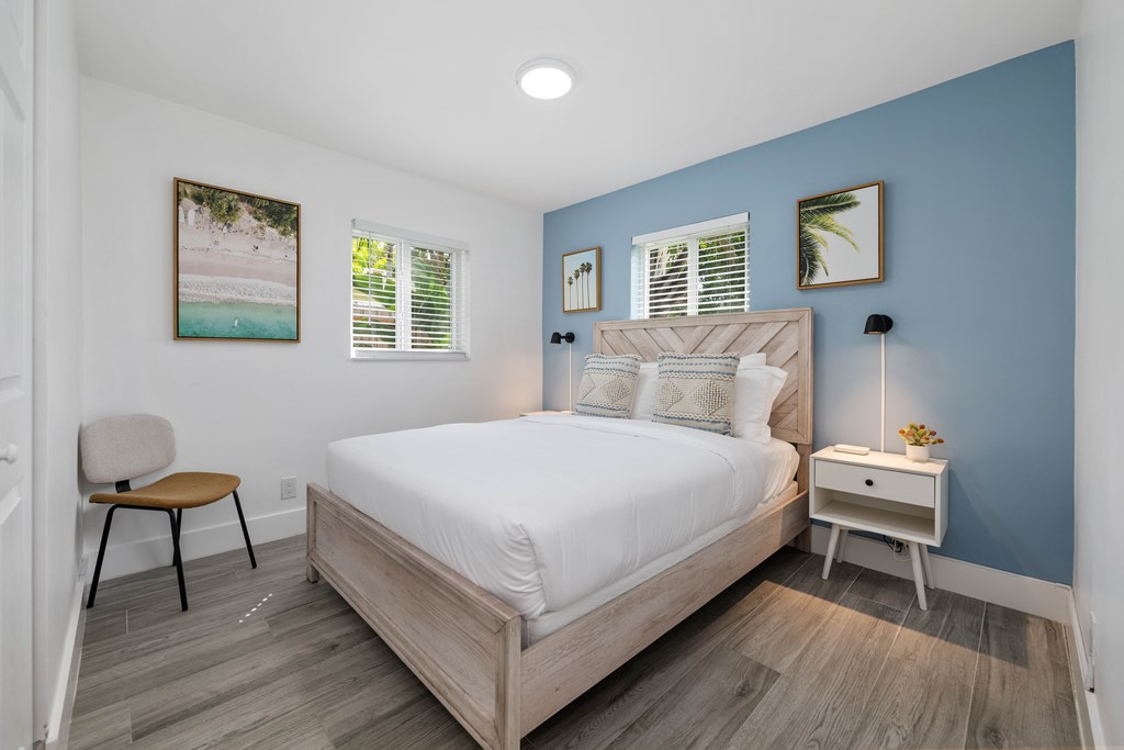 A bedroom with a bed, chair, and nightstand.