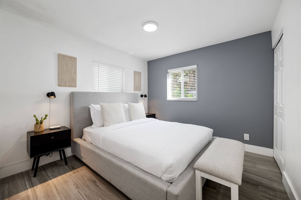 A bedroom with a large bed and a nightstand with a plant on it.