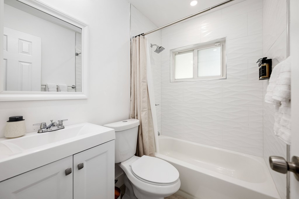 A white bathroom with a toilet, sink, and bathtub.