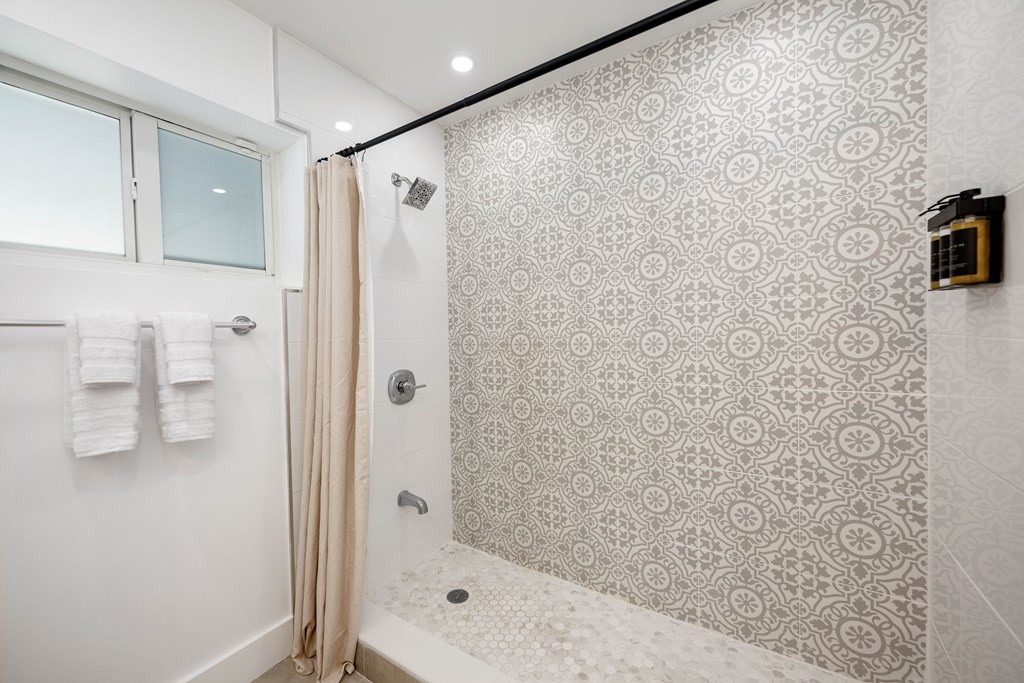 A bathroom with a shower and towel rack.
