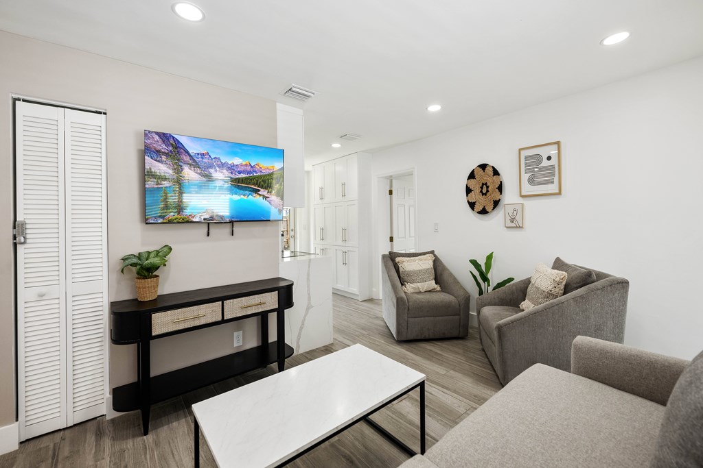 A living room with a flat screen TV mounted on the wall.