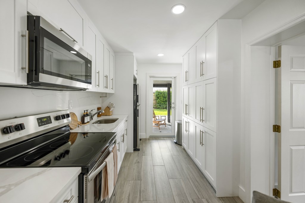 A modern kitchen with white cabinets and black appliances.