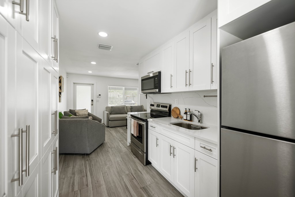 A modern kitchen with white cabinets and a stainless steel refrigerator.