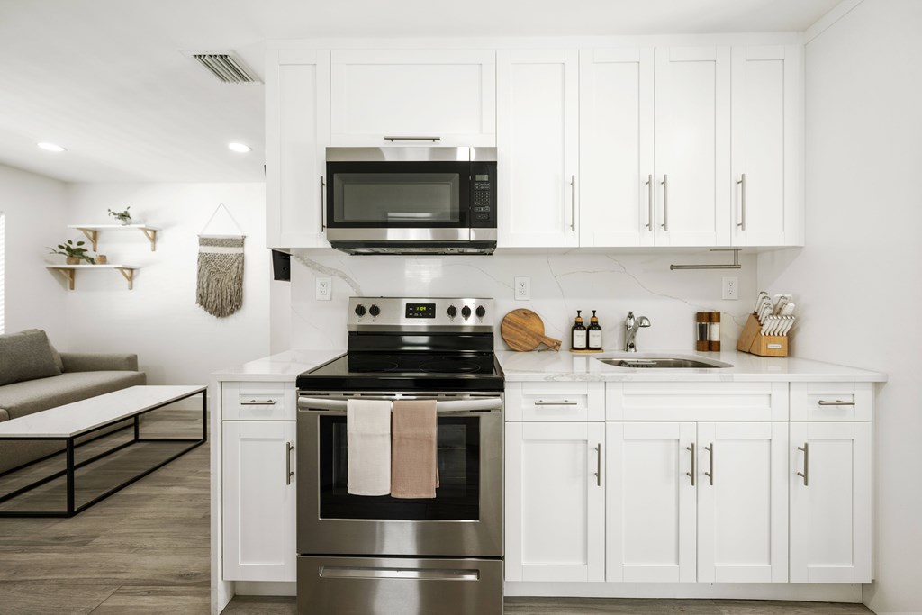 A modern kitchen with white cabinets and a stainless steel oven.