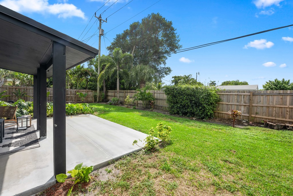 A backyard with a patio and a wooden fence.