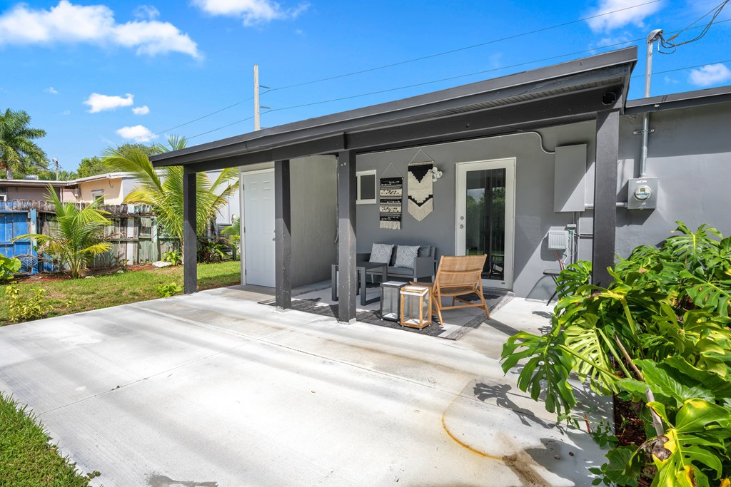 A grey house with a patio and a chair.