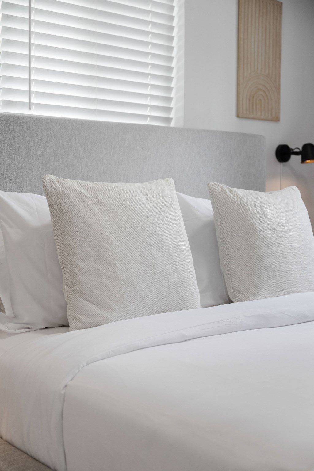 A bed with white pillows and a white headboard.