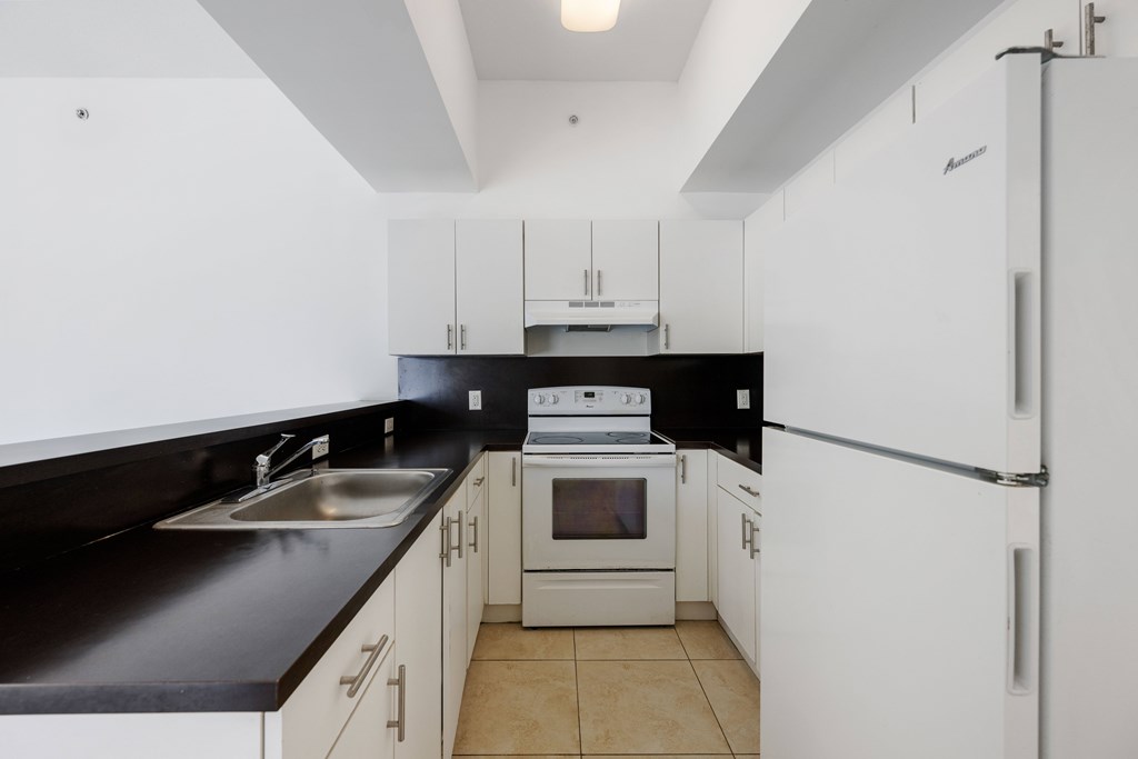 A kitchen with white cabinets and black countertops.