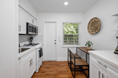 A kitchen with white cabinets and a wooden floor.