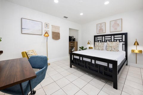 A bedroom with a bed, chair, and lamp.