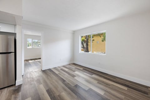 A kitchen with a refrigerator and a window with a view of trees.