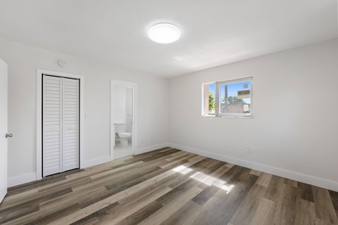 A room with a wooden floor and a window showing a blue sky.