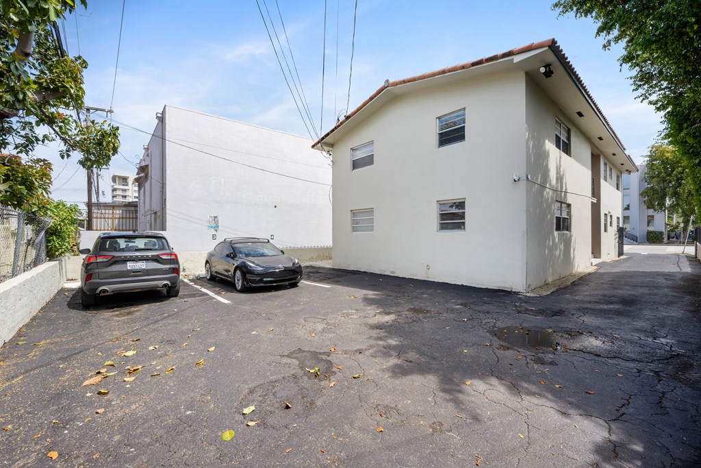 Two cars are parked in a parking lot in front of a white building.