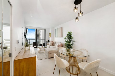A modern living room with a glass table and white chairs.
