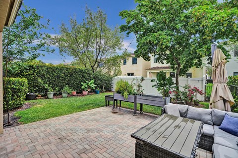Private back patio with a bench and a table with a cushion on it.