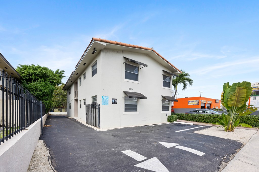 A white house with a black gate and a driveway with white arrows painted on it.